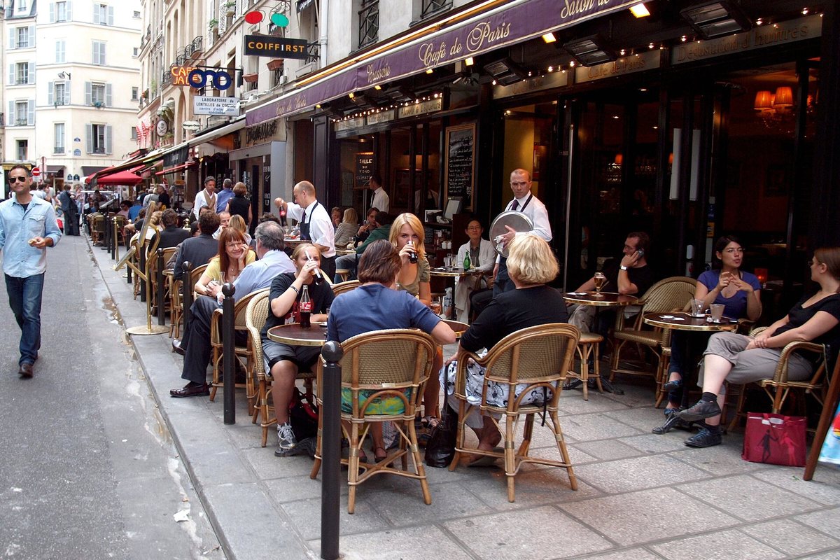 Customers seated at a cafe terrace on Rue de Buci in Paris