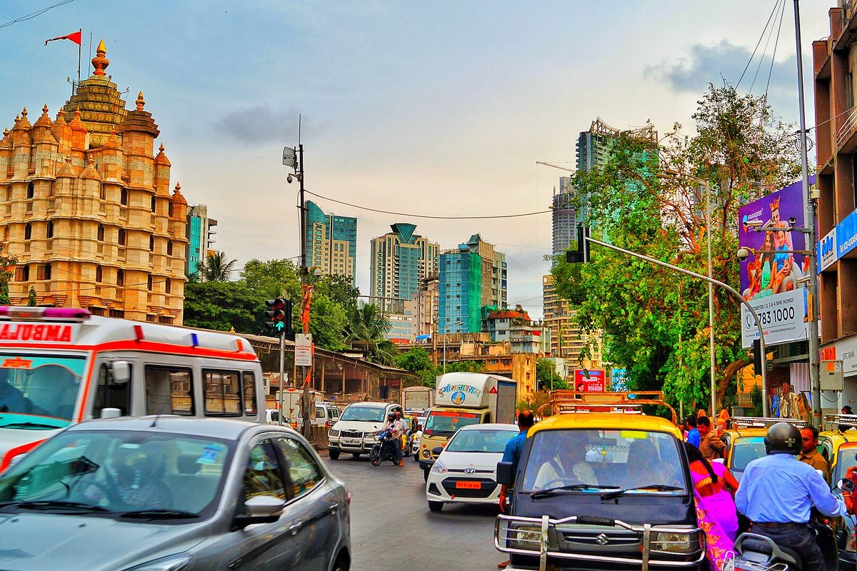 Traffic passes a temple and street stalls in Mumbai